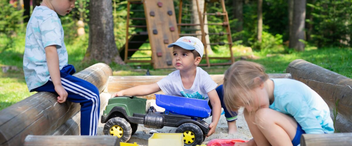 Eingezäunter Sandbereich unter Bäumen – Spielplatz am Wasserturm in Prenzlauer Berg