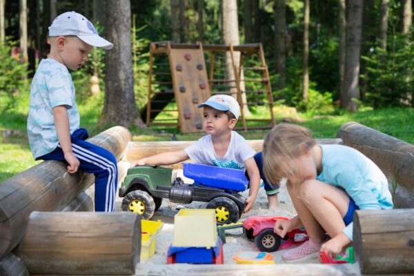 Eingezäunter Sandbereich unter Bäumen – Spielplatz am Wasserturm in Prenzlauer Berg