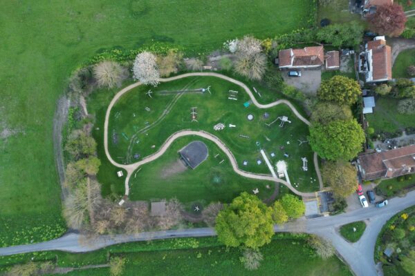 Holzspielgeräte auf einer Wiese am Dorfrand – Spielplatz Lübarser Felder in Alt-Lübars