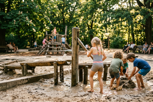Kinder an Wasserpumpe mit Matschrinnen – Wasserspielplätze Berlin Guide