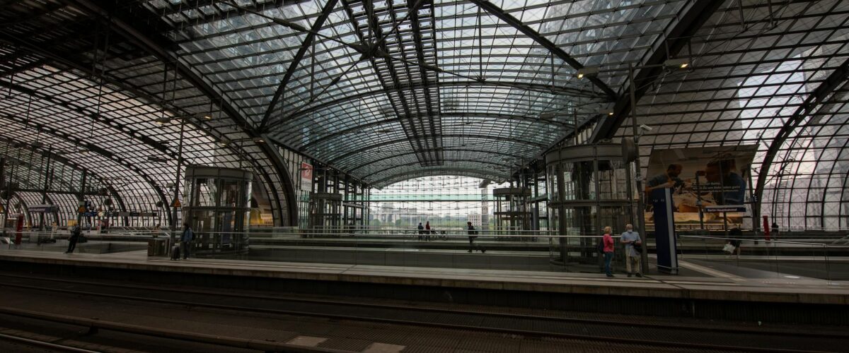 Die moderne Empfangshalle des Berlin Ostbahnhof mit Reisenden, die auf die Anzeigetafeln blicken.