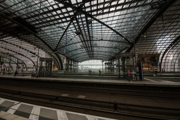 Die moderne Empfangshalle des Berlin Ostbahnhof mit Reisenden, die auf die Anzeigetafeln blicken.