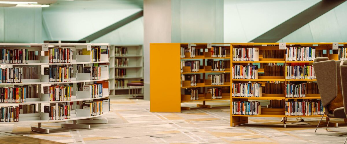Helle und moderne Innenansicht der Bibliothek Neukölln mit hohen Bücherregalen und einer einladenden Lese-Lounge.