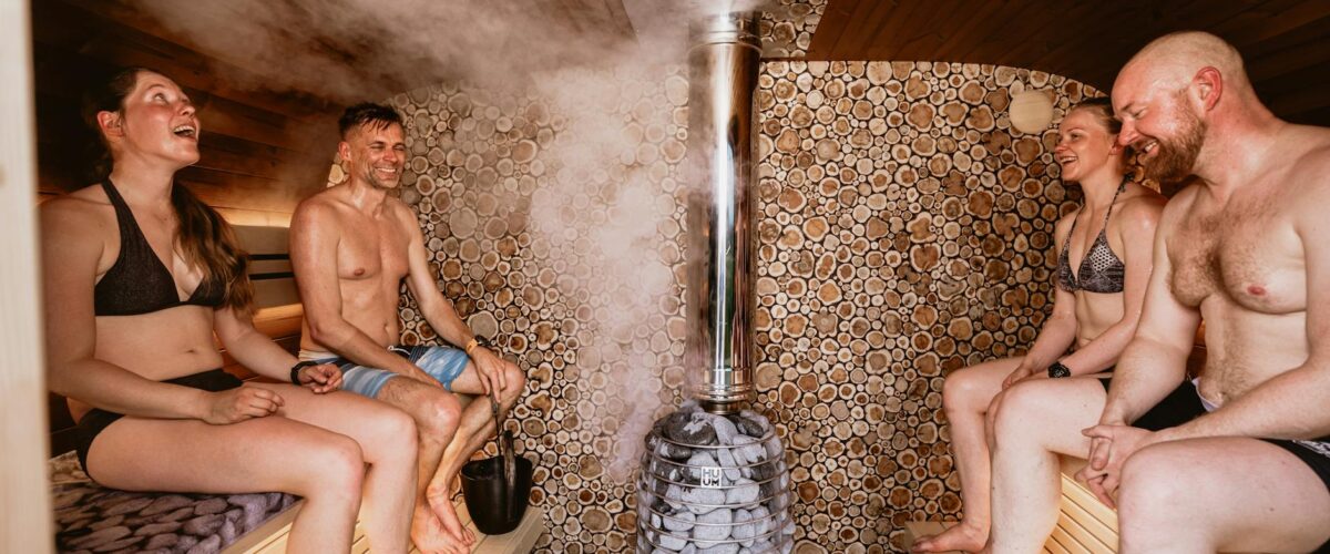 Ein Saunameister führt einen Aufguss in einer klassischen finnischen Sauna in Berlin durch, Dampf steigt von den heißen Steinen auf.