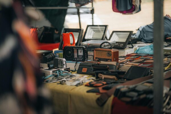 Ein belebter Stand auf dem Flohmarkt Boxhagener Platz, an dem Besucher in Kisten mit Second-Hand-Waren und Vintage-Artikeln stöbern.