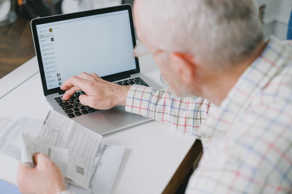 Ein &auml;lterer Herr sitzt an einem Laptop und f&uuml;llt konzentriert ein Online-Formular f&uuml;r die Steuererkl&auml;rung f&uuml;r Rentner aus.
