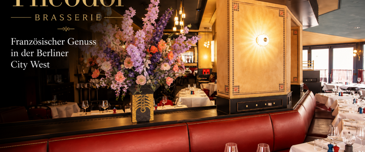 Stilvoller Restaurantbereich der Théodor Brasserie Berlin mit roten Lederbänken, weißen Tischen und Blumenarrangement