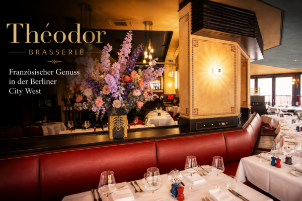 Stilvoller Restaurantbereich der Théodor Brasserie Berlin mit roten Lederbänken, weißen Tischen und Blumenarrangement