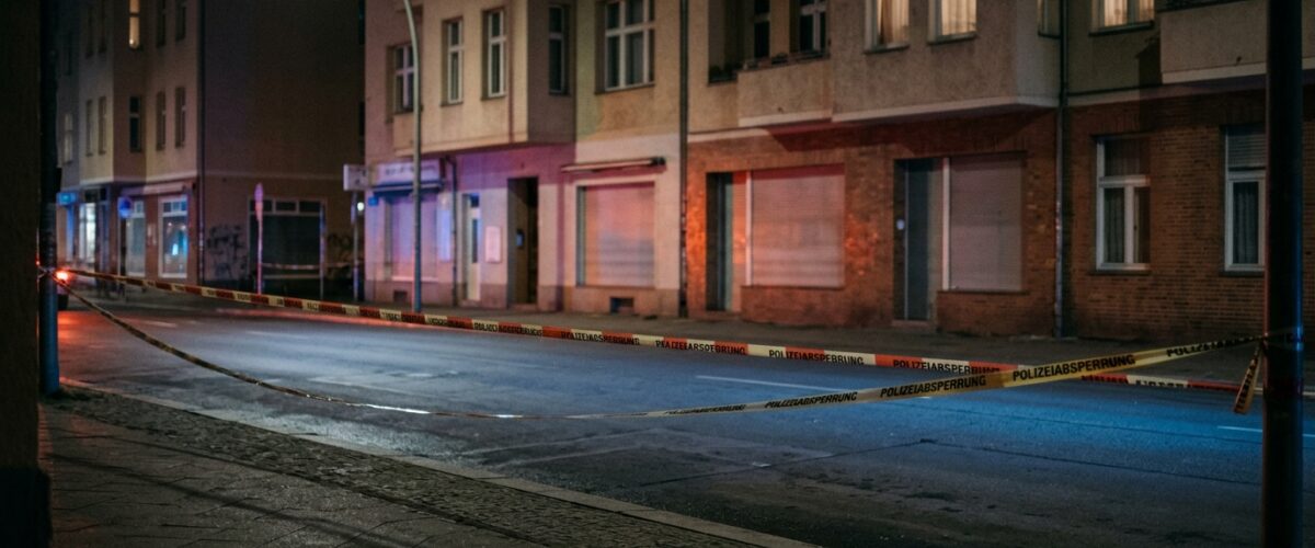 Menschenhandel in Restaurants Berlin: Blaulicht und Absperrband bei Nacht an einer menschenleeren Berliner Straße, saubere leere Fahrbahn ohne Gegenstände und ohne Spuren