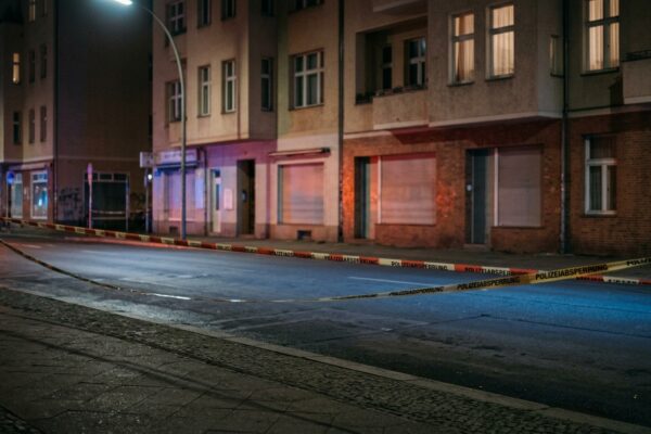 Menschenhandel in Restaurants Berlin: Blaulicht und Absperrband bei Nacht an einer menschenleeren Berliner Straße, saubere leere Fahrbahn ohne Gegenstände und ohne Spuren