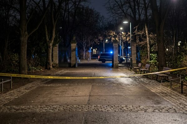 Raubüberfall im Mauerpark: Blaulicht und Absperrband bei Nacht an einem menschenleeren Park-Eingang, saubere leere Wege ohne Gegenstände und ohne Spuren