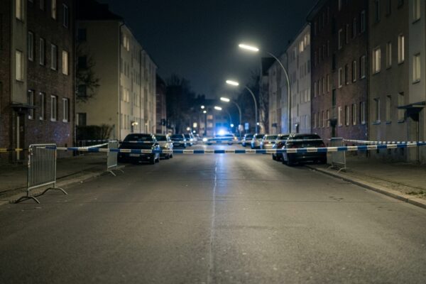 Scheinankäufe Drogenlieferdienst Berlin: Blaulicht und Absperrband bei Nacht an einer menschenleeren Berliner Straße, saubere leere Fahrbahn ohne Gegenstände und ohne Spuren