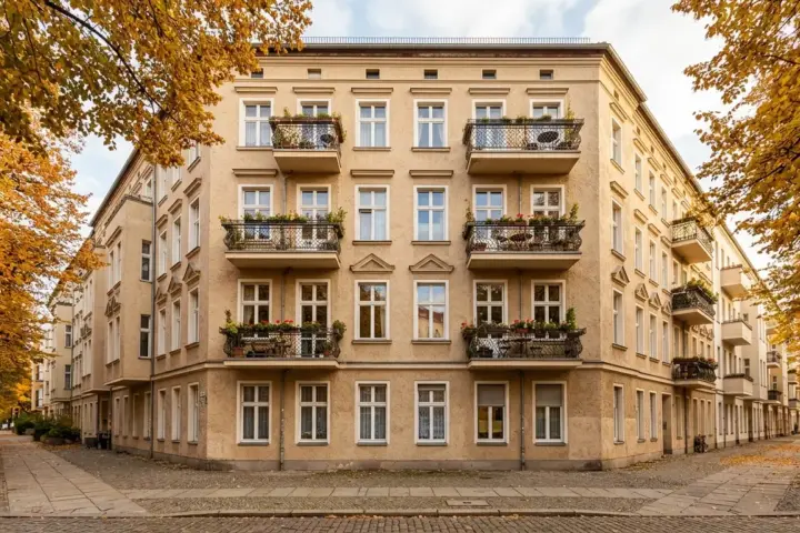 Fassade eines Berliner Mehrfamilienhauses mit Balkonen und Herbstlaub vor Fenstern im warmen Nachmittagslicht
