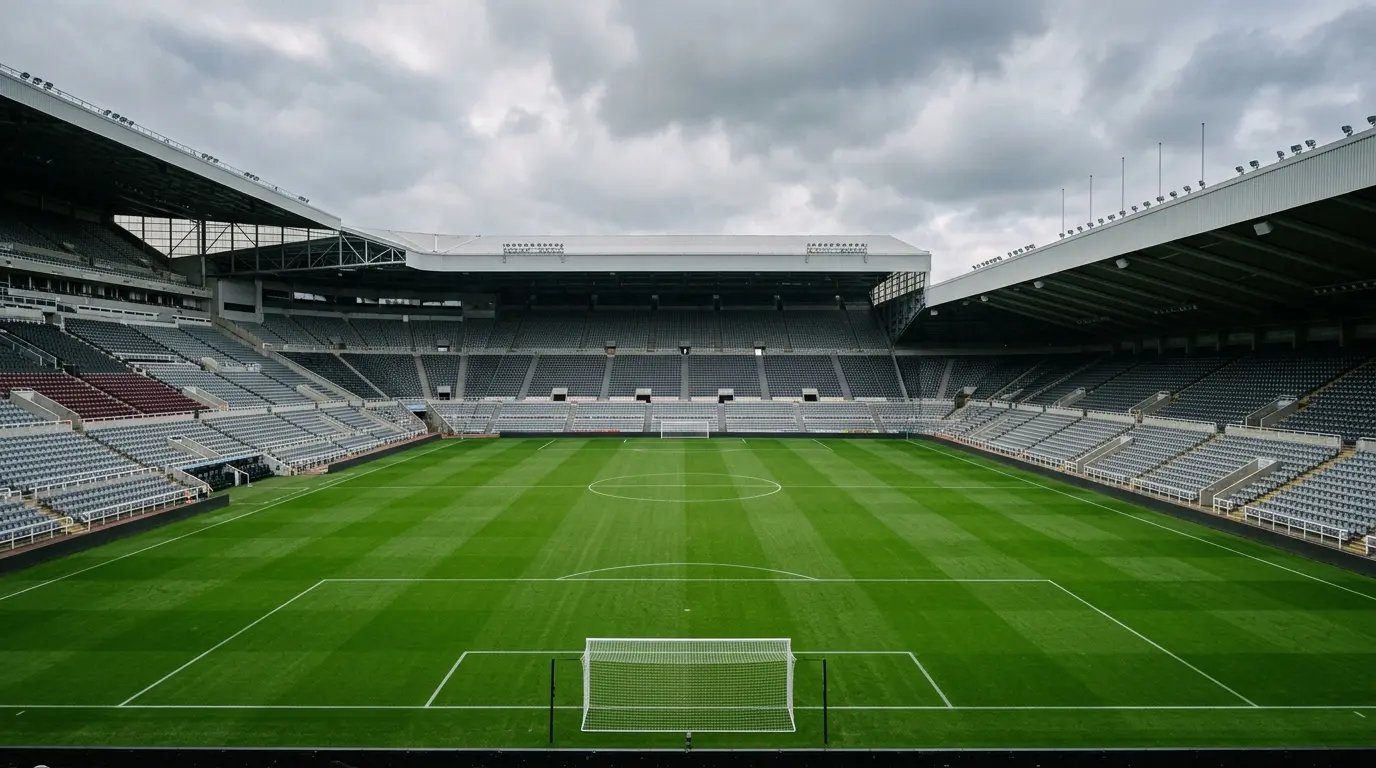 Blick über einen gepflegten grünen Rasen auf leere Tribünenränge eines großen Fußballstadions bei Tageslicht.